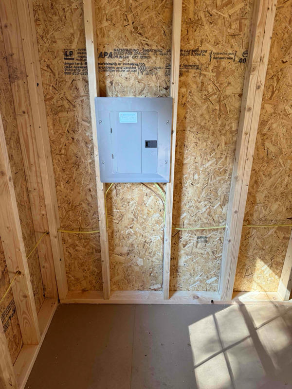 An electrical sub-panel installed in a wood framed shed building.