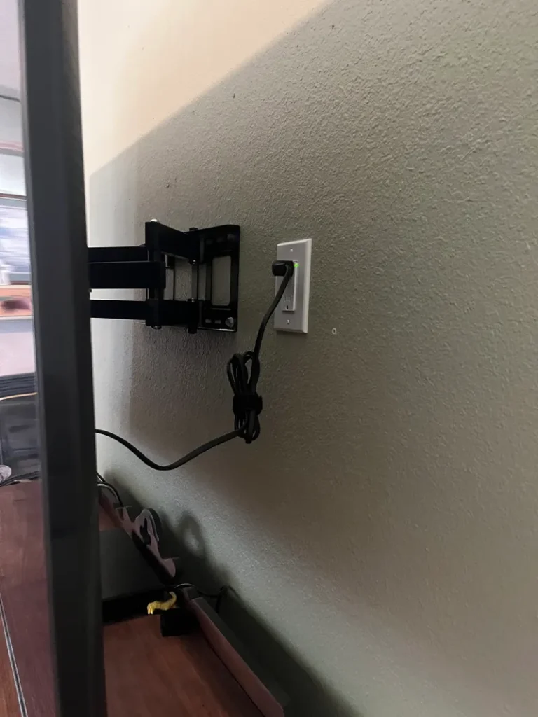 A surge protector receptacle installed behind a wall mounted TV.