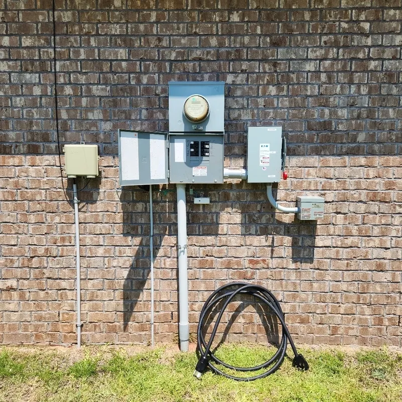 A main electrical service panel with a manual transfer switch, inlet, and cord for a portable generator connection.
