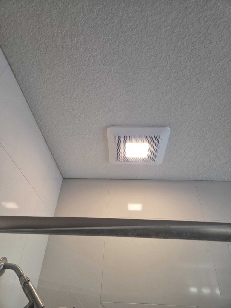 A bathroom exhaust fan with light installed above a shower in a condo in Pensacola, FL.