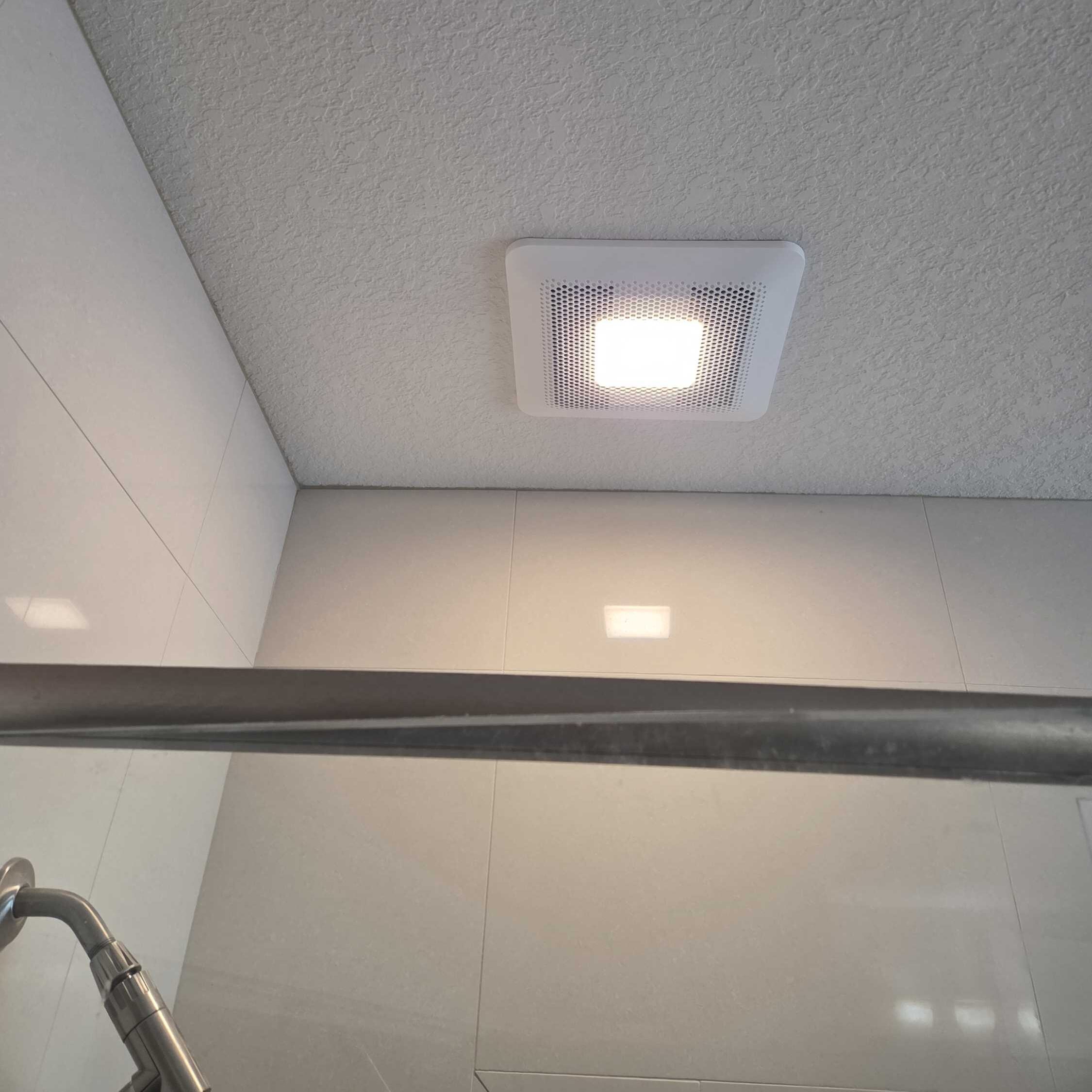 A bathroom exhaust fan with a light installed over a shower at a condo in Pensacola, FL.