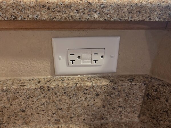 A GFCI outlet in a the wall space above a kitchen counter.