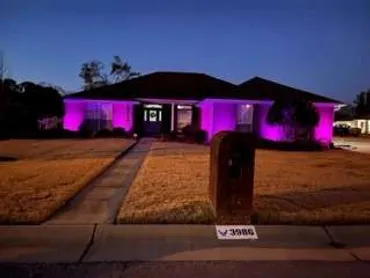 A night time photo of purple outdoor uplighting shining on the front of a home in Pace, FL.
