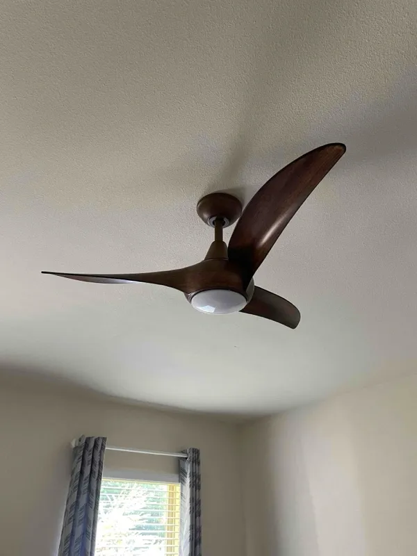 A three bladed wood ceiling fan.