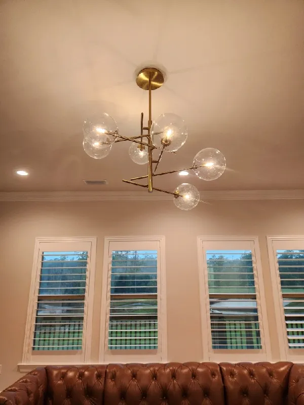 A gold light fixture with clear globes radiating out at different angles from the center.
