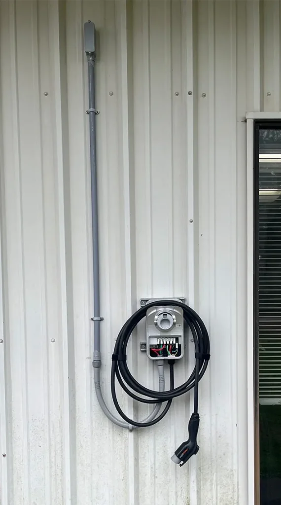 An EV charger unit mounted to an exterior wall at a business in Pensacola, FL.