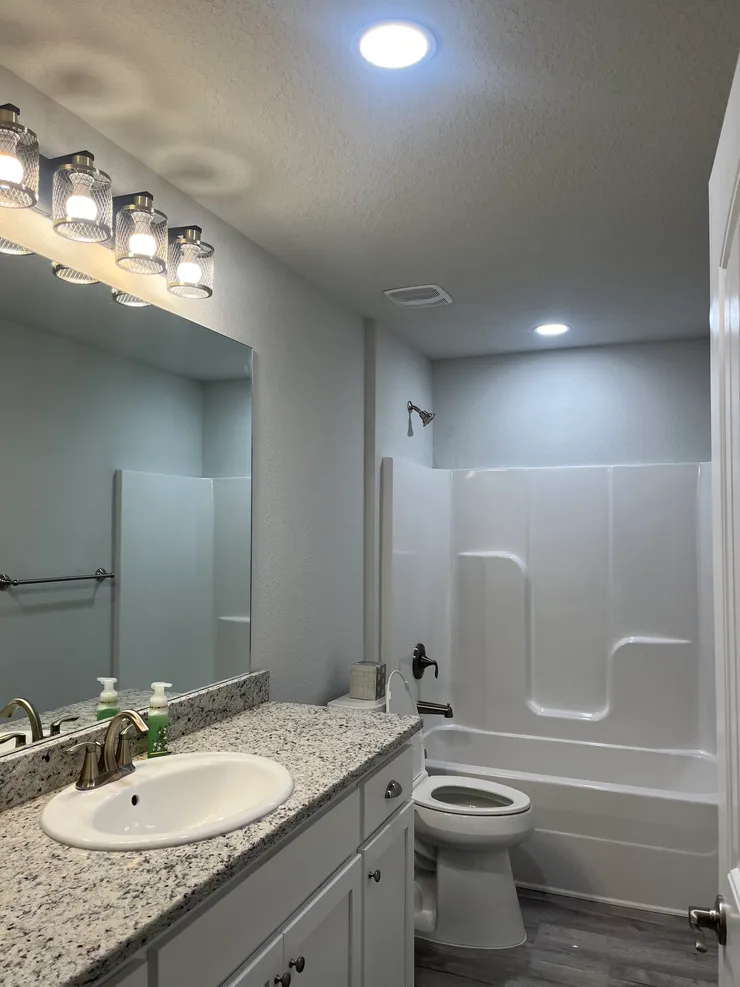 A vanity light and recessed lighting installed in a bathroom.