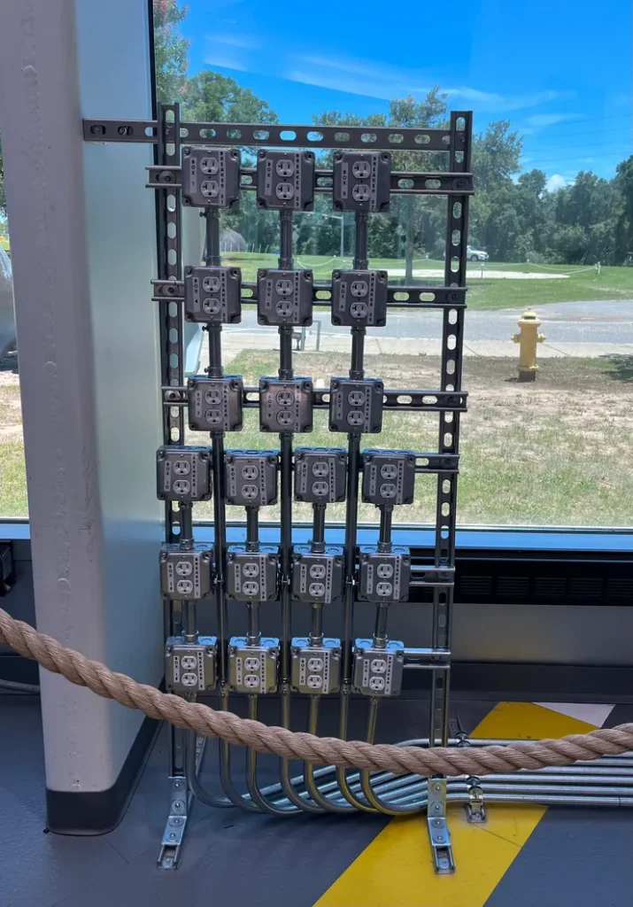 Twenty-one receptacles in individual metal boxes installed on a unistrut rack.