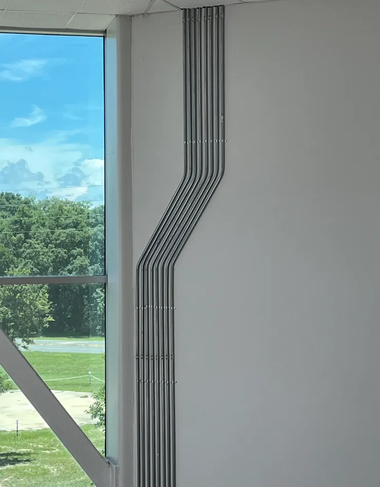 Eight runs of EMT electrical conduit installed on a high wall with two separate forty-five degree bends.