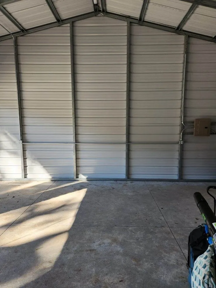 An electrical panel, receptacles, and conduit installed in a metal shed building.
