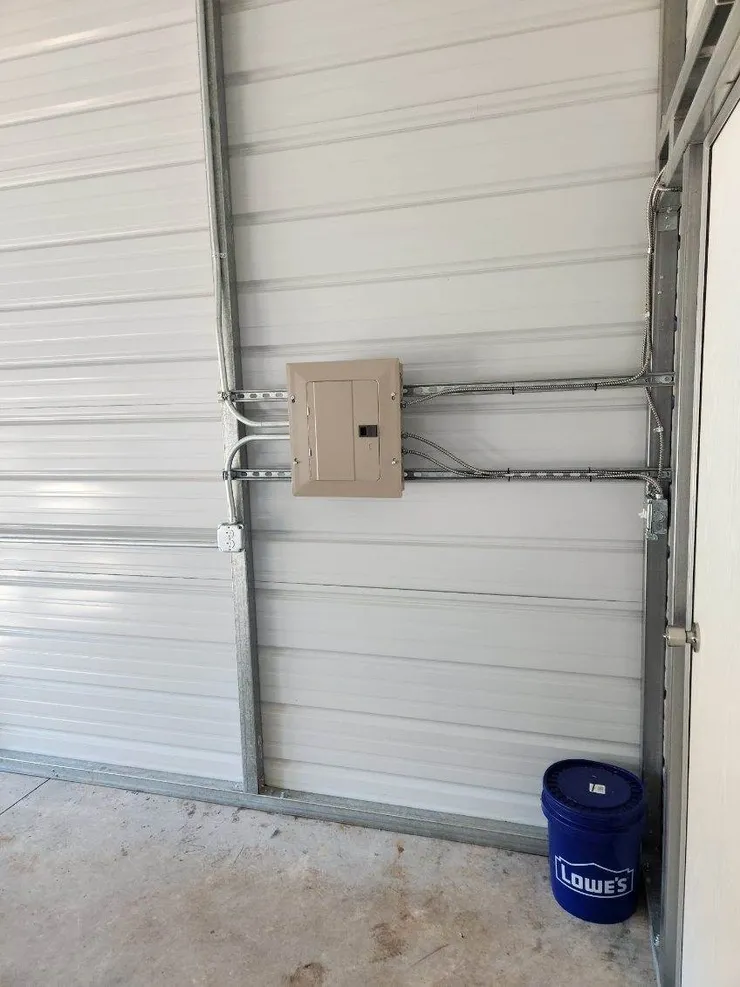 An electrical panel, wiring, and receptacles installed in a metal shed.