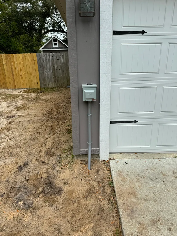 A head on view of a RV receptacle installed on an exterior wall beside a garage door.