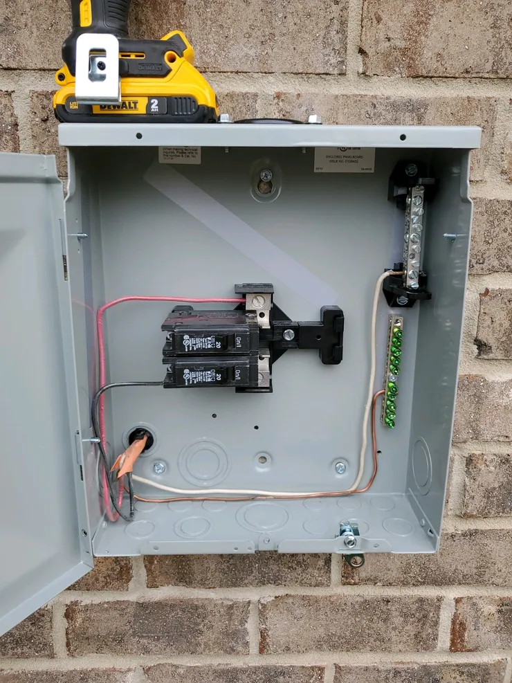 An electrical sub-panel installed on an exterior brick wall.