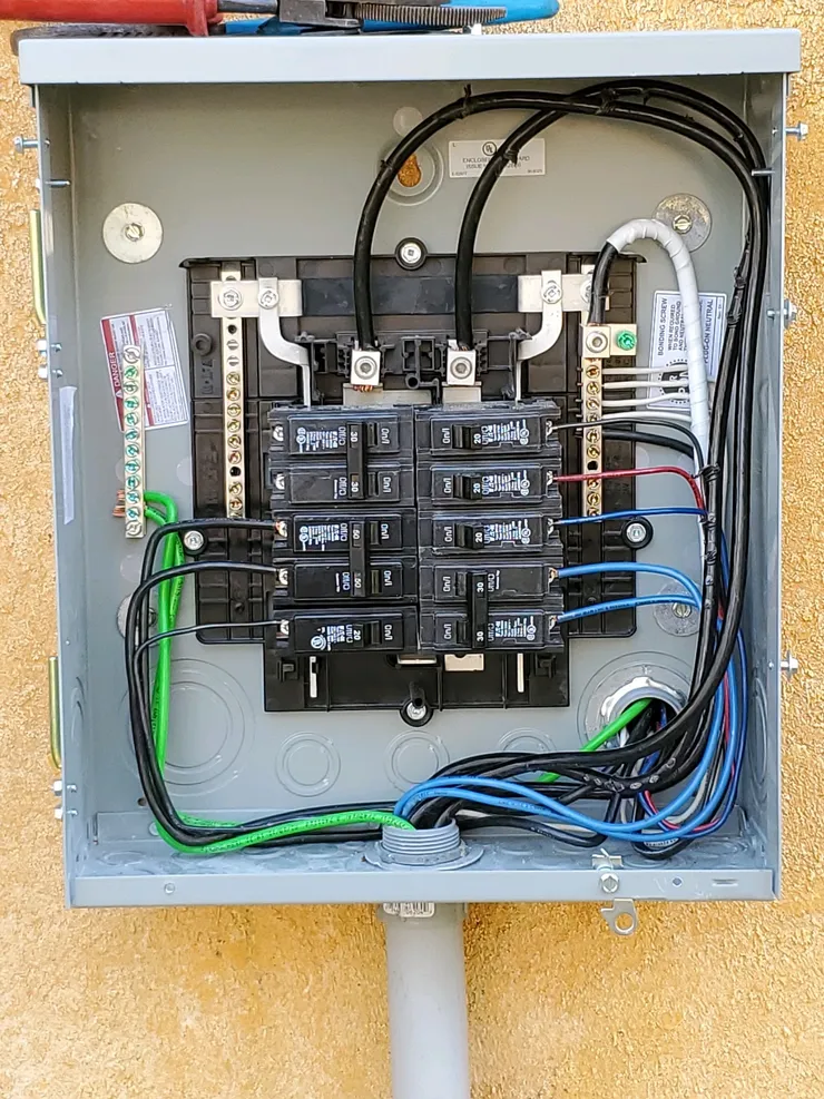 An electrical sub-panel installed on an exterior stucco wall.