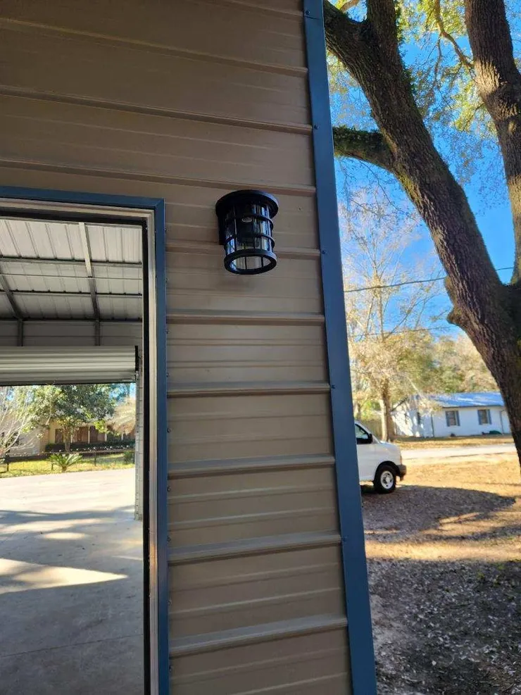 A light fixture installed on the exterior of a metal shed next to the door.