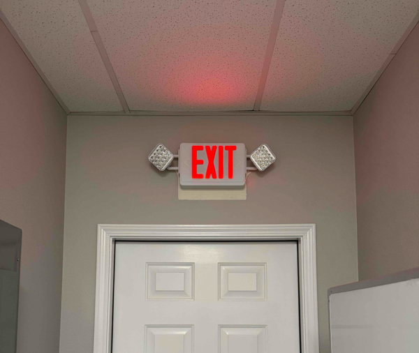 Combination exit sign and emergency light in a commercial business space.