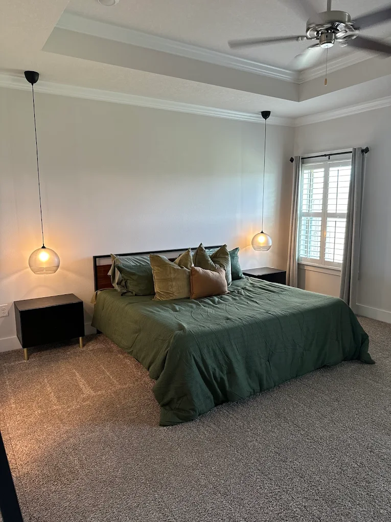 Two long pendant light fixtures installed on either side of the head of a bed.