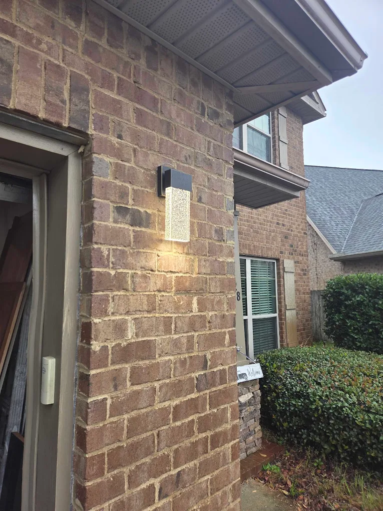 A modern rectangular coach light installed outside of a home garage roll up door.